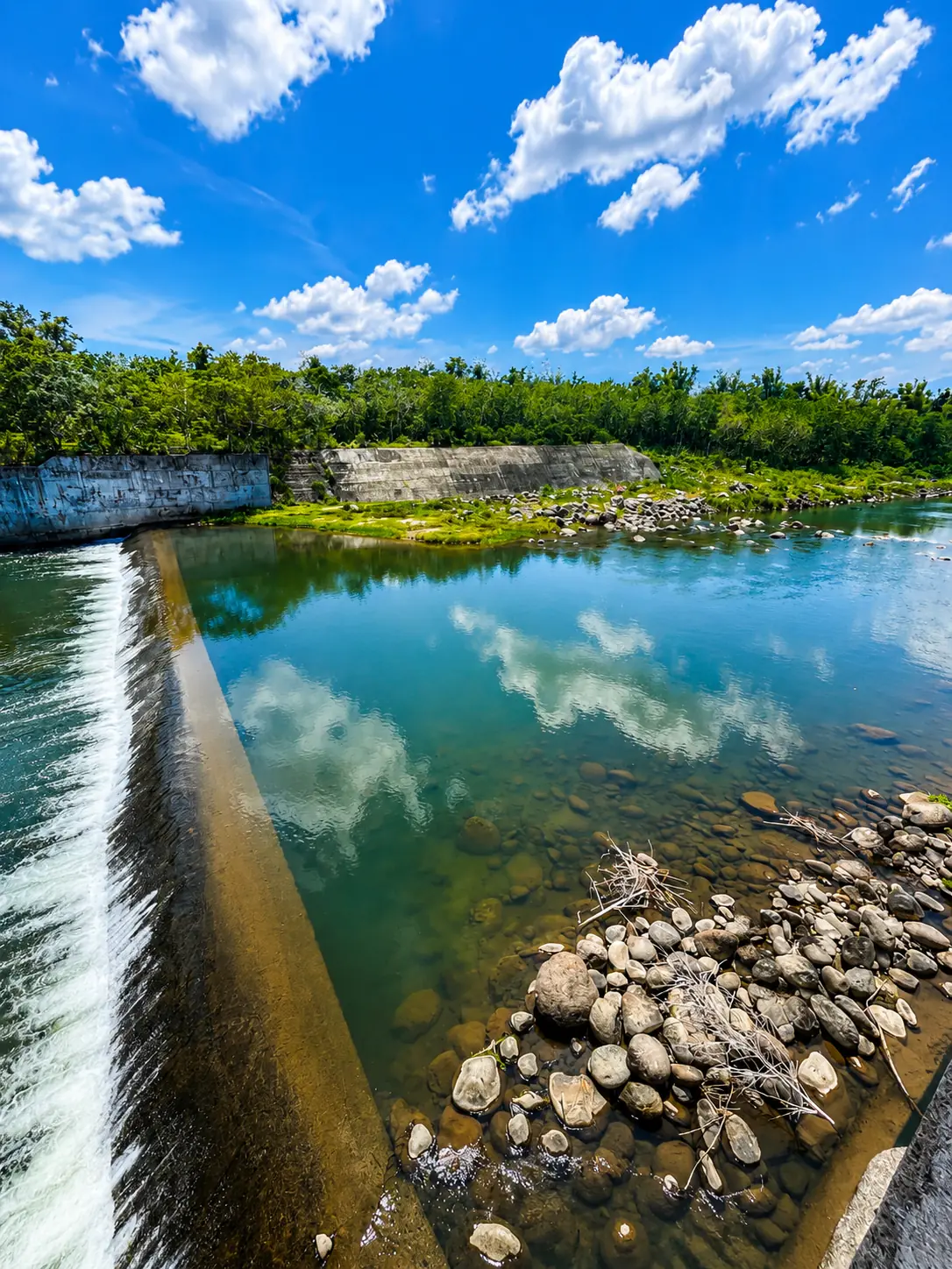 The Malogo River with crystal-clear water, blue sky, and smooth river stones