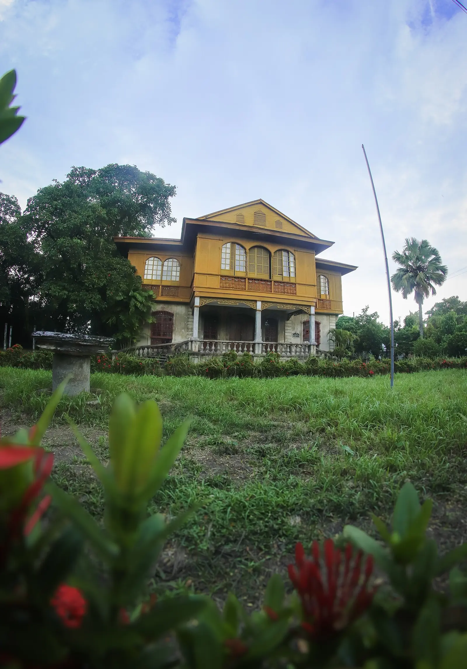 The Balay Negrense facade in Silay, a white house with a red roof and arched windows, seen from the street