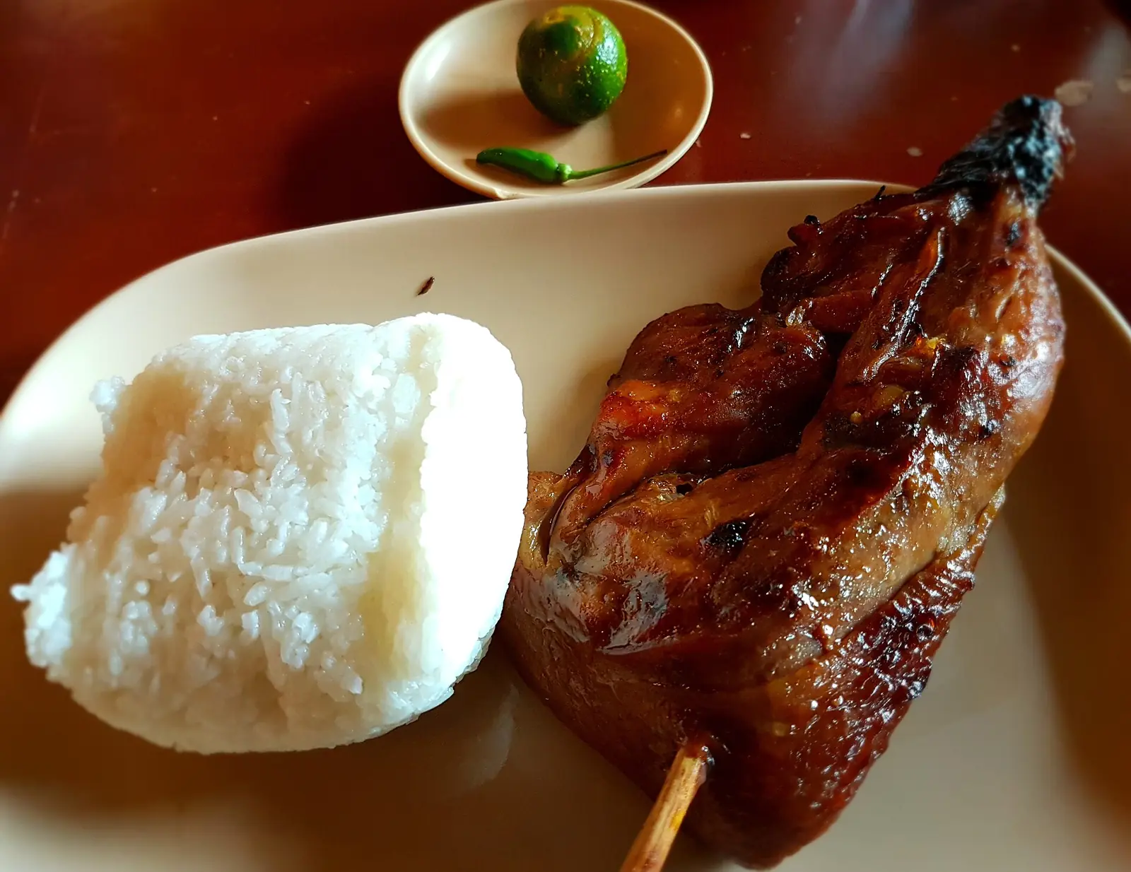 Chicken inasal on a plate with garlic rice and a red sauce
