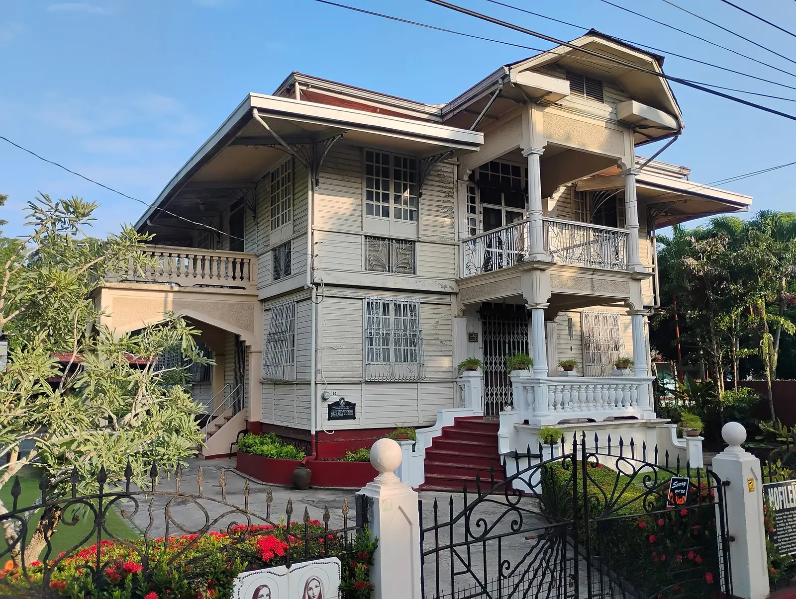 The white Hofileña Ancestral House in Silay, with capiz windows and a sign by the gate