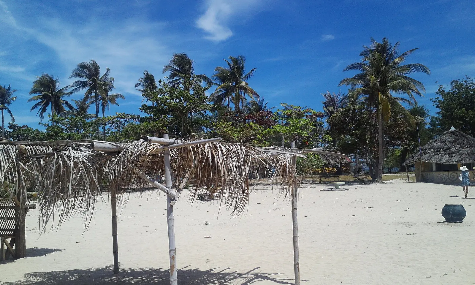 The white sand of Lakawon Island, with shallow turquoise water and a line of cottages