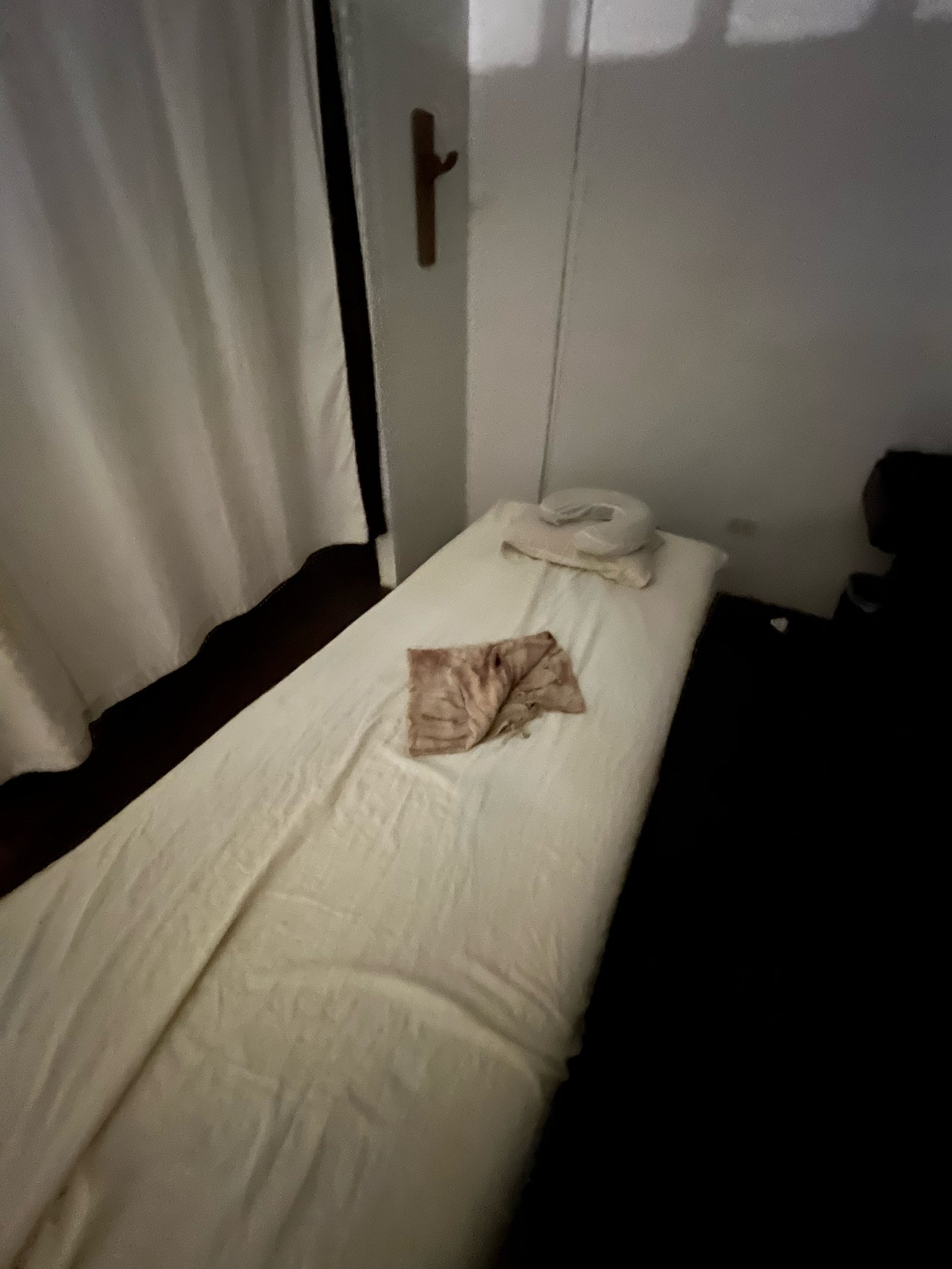 Spa Natura massage room at Mambukal: a bed in white linen, a pale curtain, and the forest outside the window.